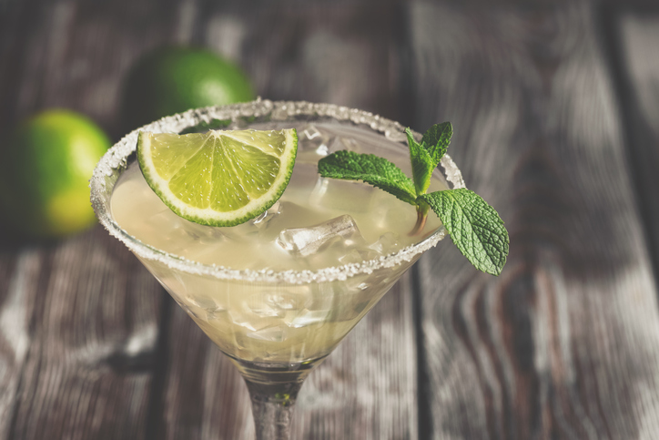 Close up margarita cocktail with lime, mint and ice. Wooden old background. Side view, selective focus. Toned photo