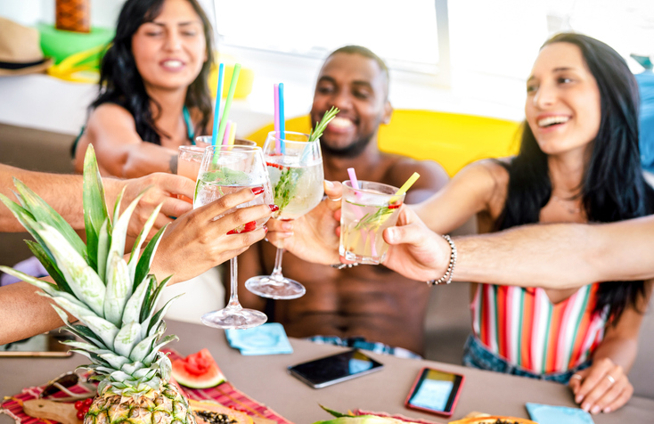 Trendy people toasting fancy cocktails at boat party trip - Young millenial friends having fun on luxury vacation - Travel life style concept with vacationer sharing aperitif drink with tropical fruit