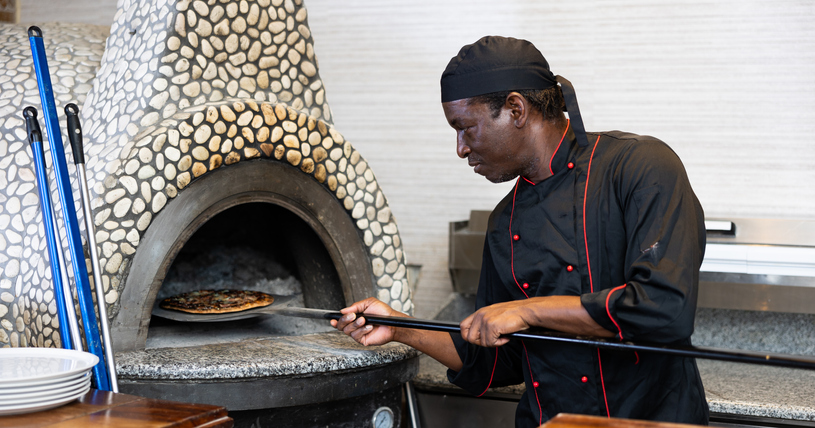 Portrait of african american chef man baking pizza in oven