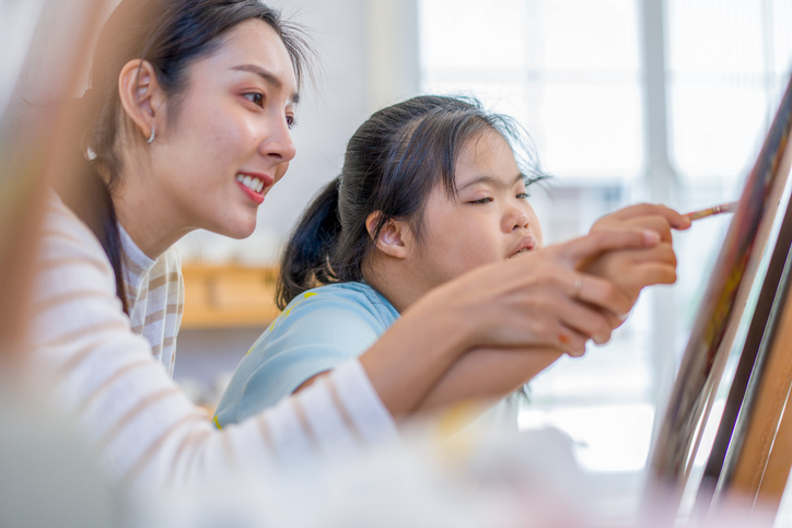 The caregiver on the art therapy of a girl with a mental disability.