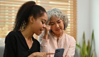 Young African daughter-in-law explains to grandmother how to use a smartphone or some applications and suggestions on how to use a social network. Teaching the older generation to use a new technology