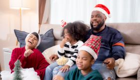 Happiness African family mom and dad and daughter watching tv and laughing with fun and enjoyment in the living room at home, family leisure with television for comfortable in Christmas day.