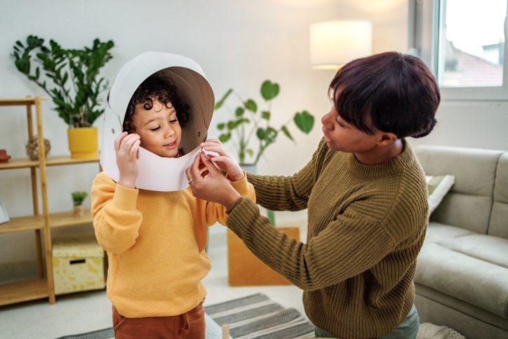 Mother and son playing with carboard astronaut helmet at home