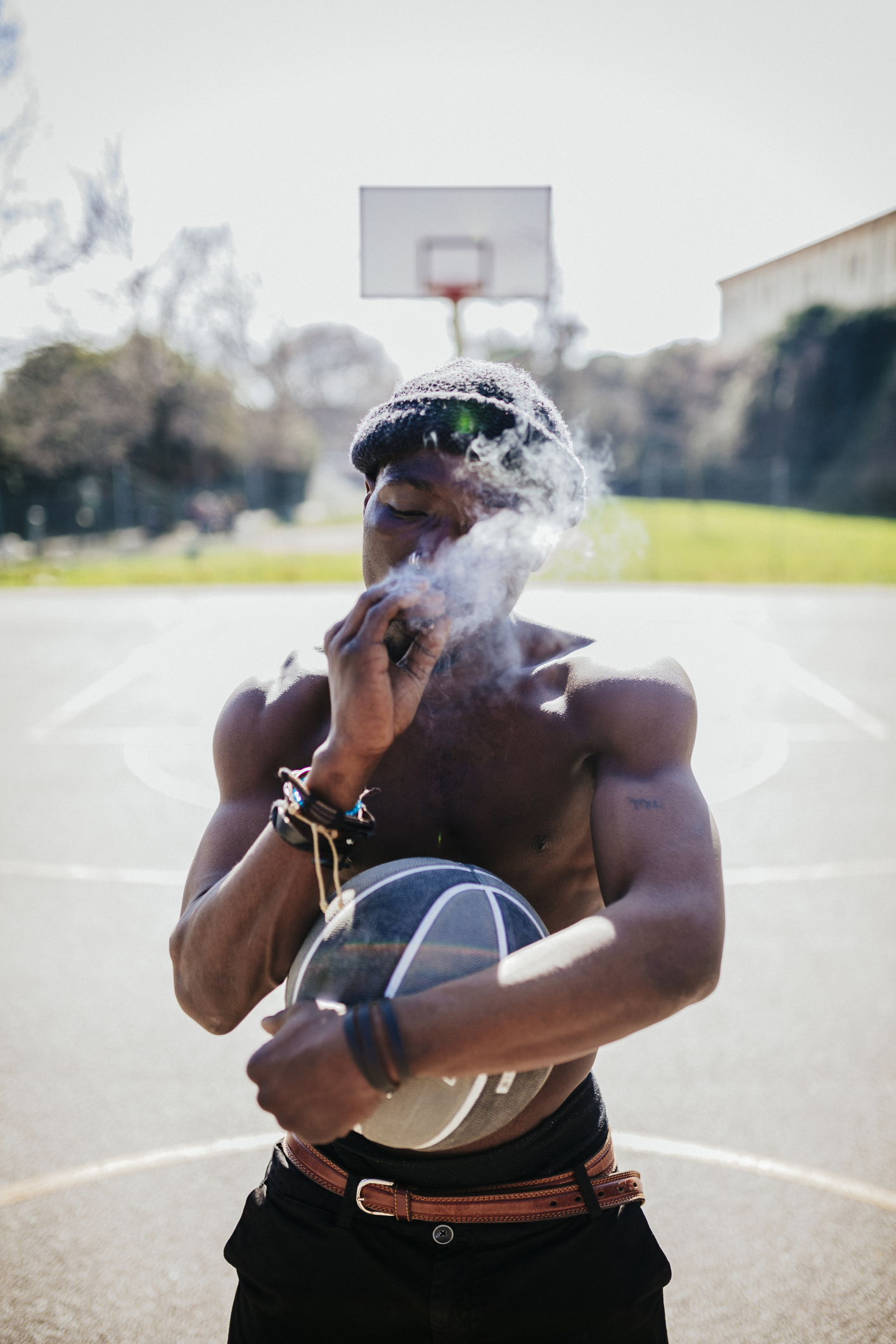 Barechested basketball player on court smoking a joint