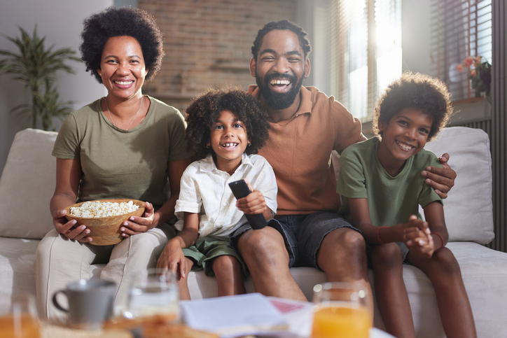 Happy African American family watching TV at home.