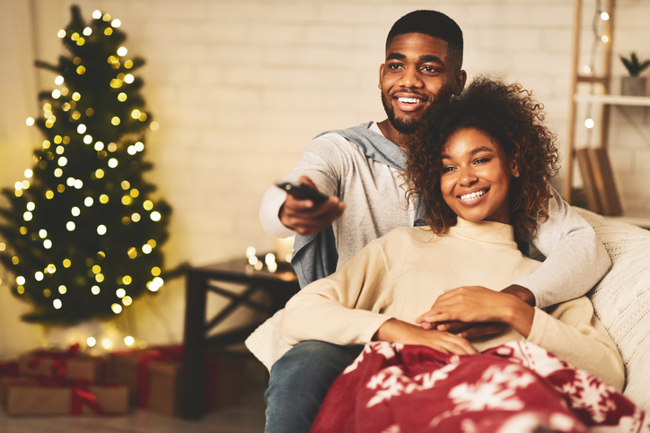 Christmas time concept. Afro cute couple watching TV