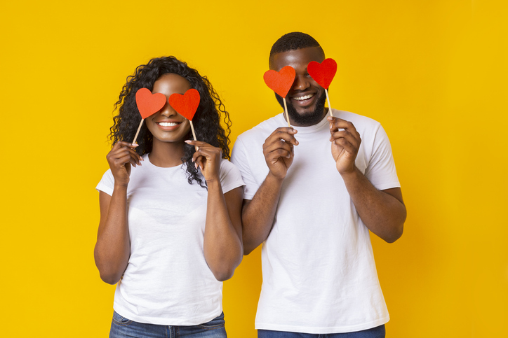 Black couple closing eyes with red love hearts