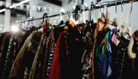 Garage Sale With Thrifting And Second Hand Silk Dresses And Blouses On Clothing Racks. Full Frame, Ambient Light