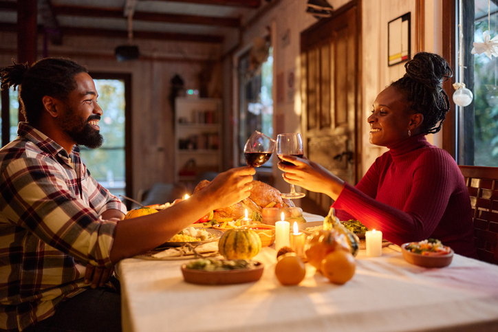 Happy black couple toasting during Thanksgiving meal in dining room.