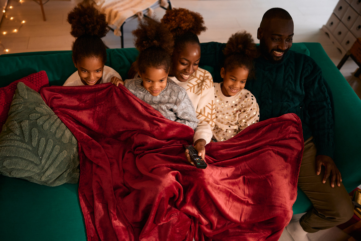 Black family watching Christmas movies on living room couch