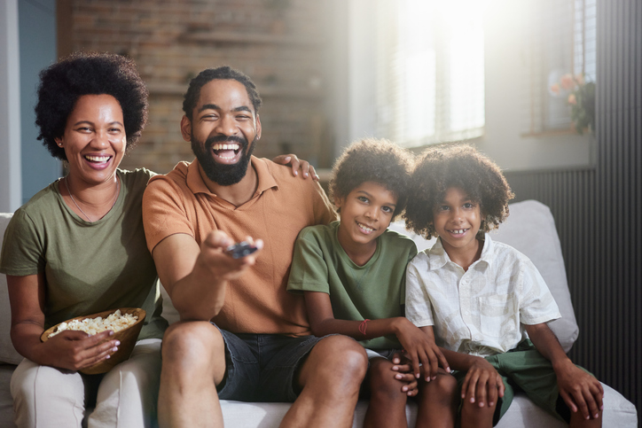 Happy African American family watching TV at home.