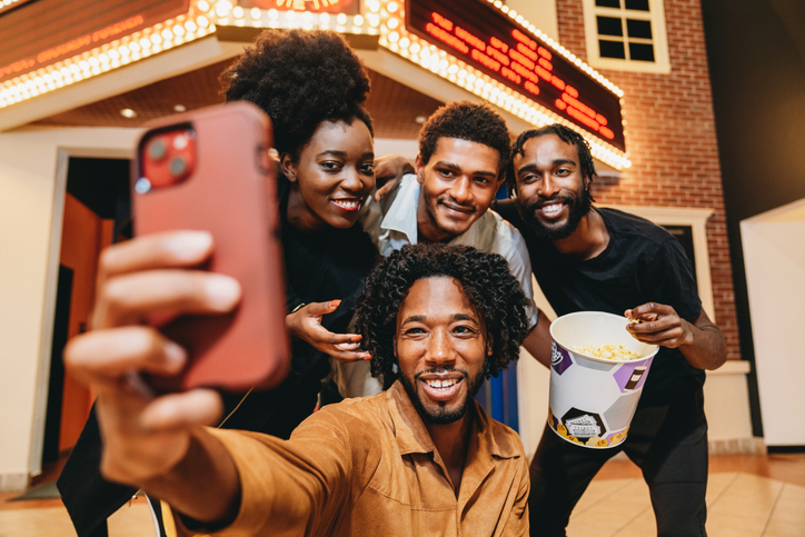 Four friends taking a selfie at movie theater entrance