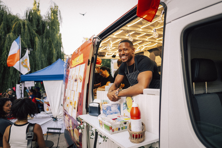 Happy male owner looking away while standing in food truck