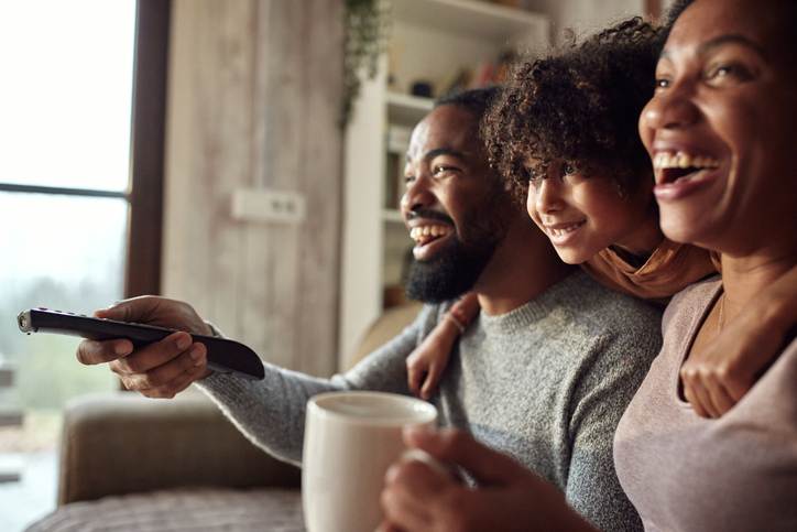Happy black family watching TV at home.